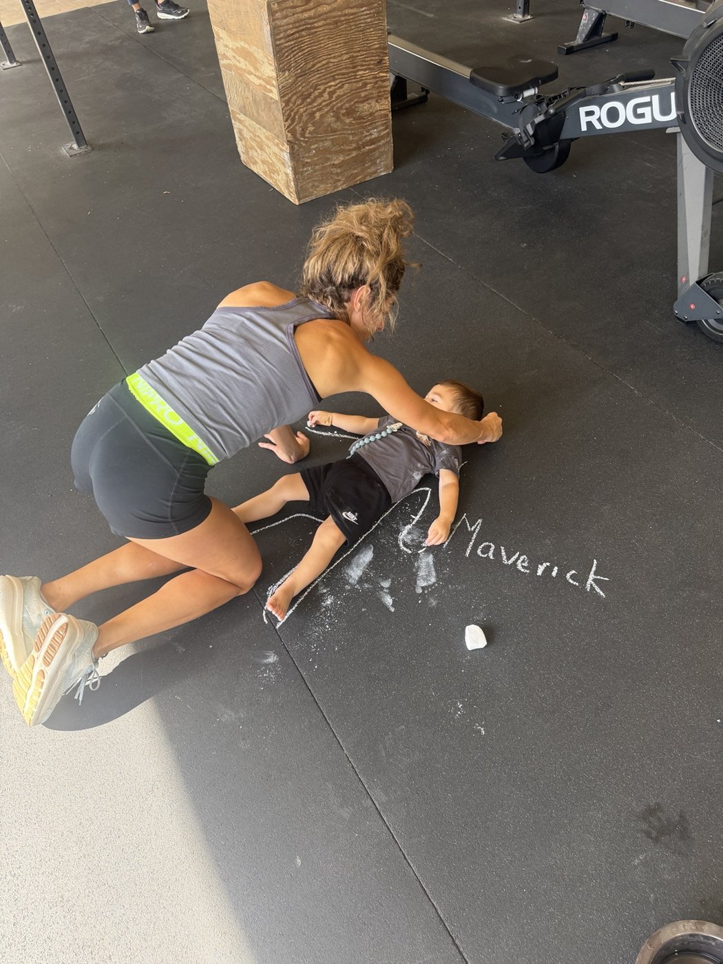 An adult and young child enjoying a chalk drawing on the gym floor